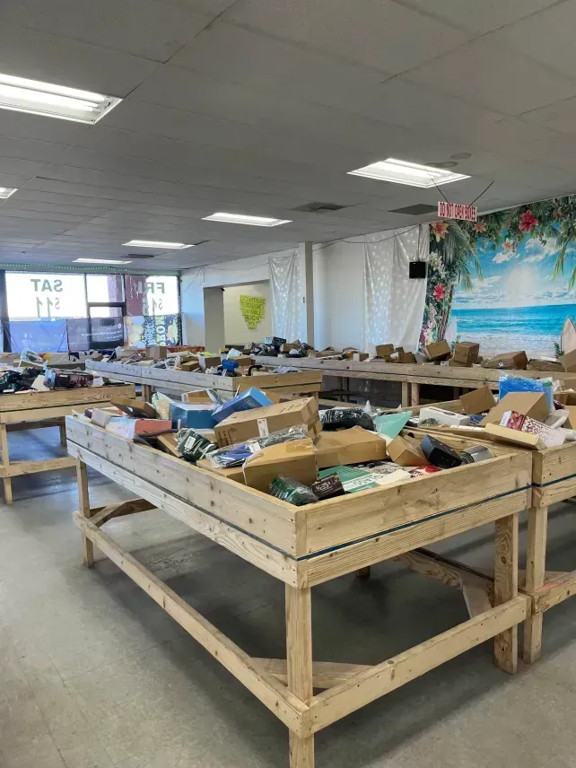 Wooden tables laden with merchandise in a brightly lit discount store.
