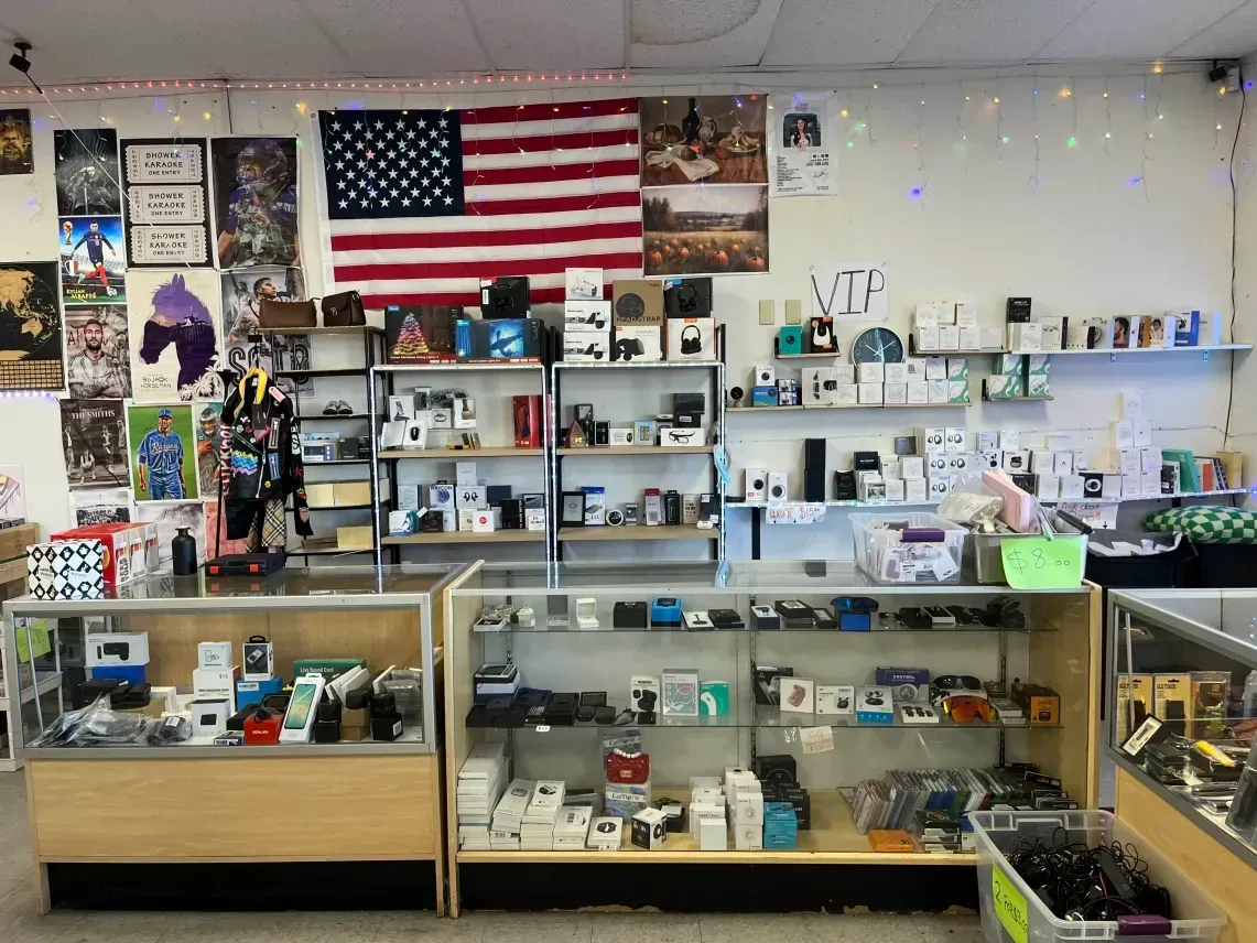 Inside a shop: electronics displayed on shelves, American flag, glass display cases with products at the VIP section.