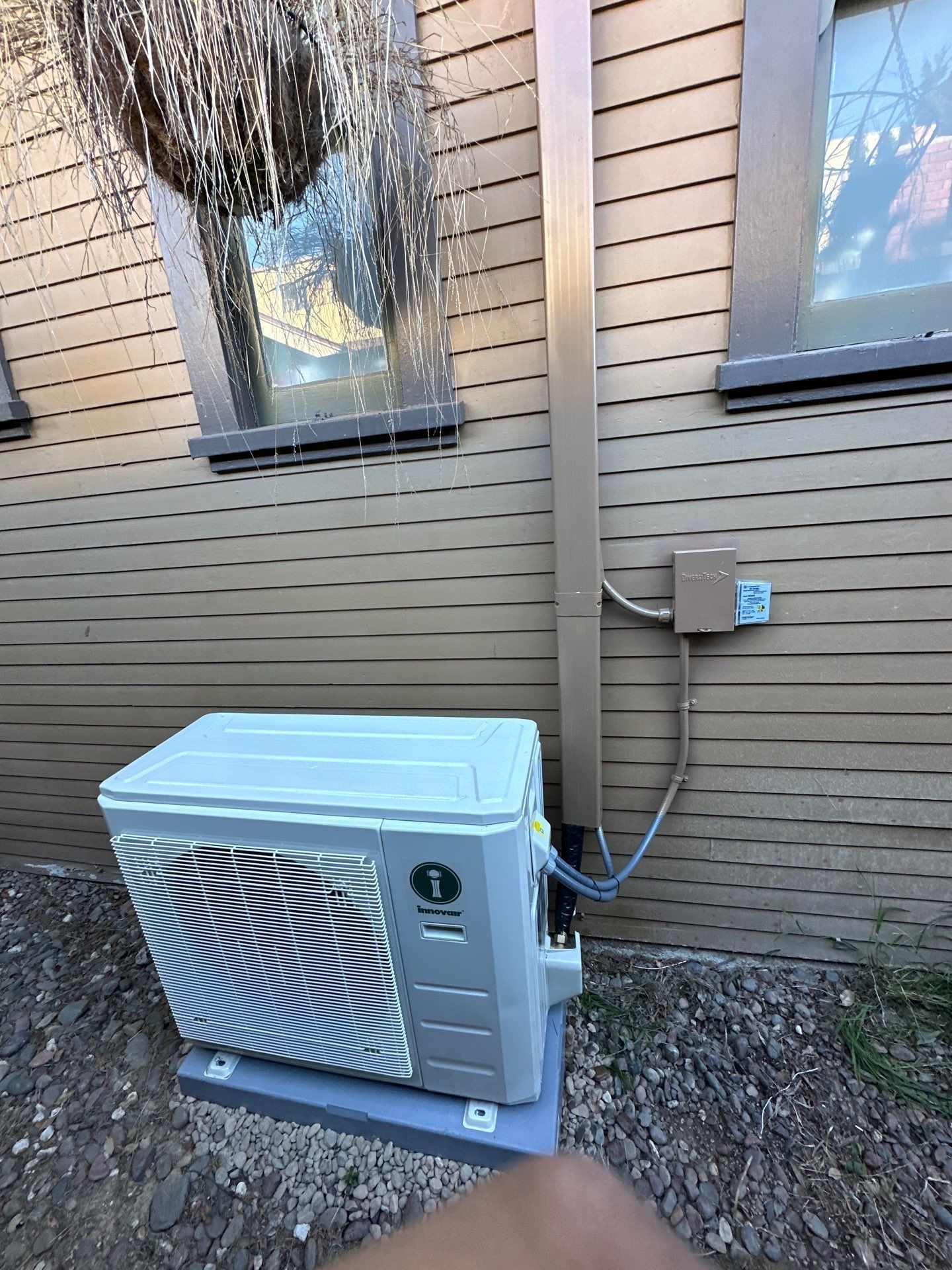 A man is working on an air conditioner outside of a building.