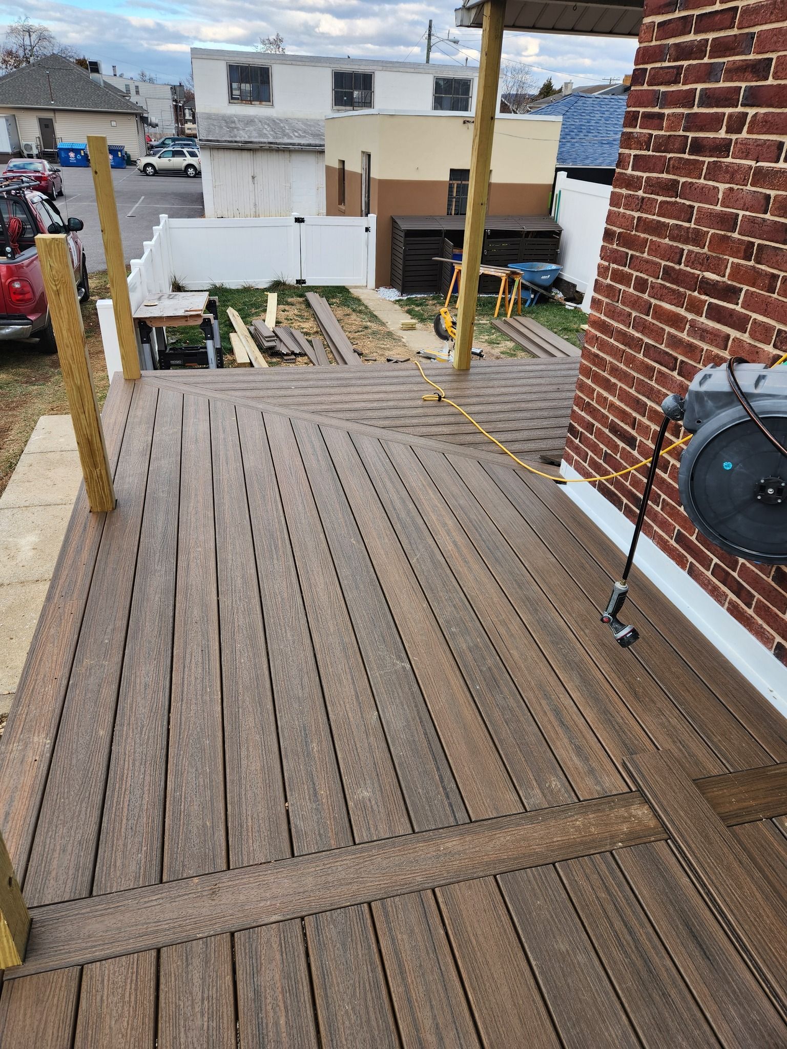 Wooden deck under construction next to a brick wall and other buildings.