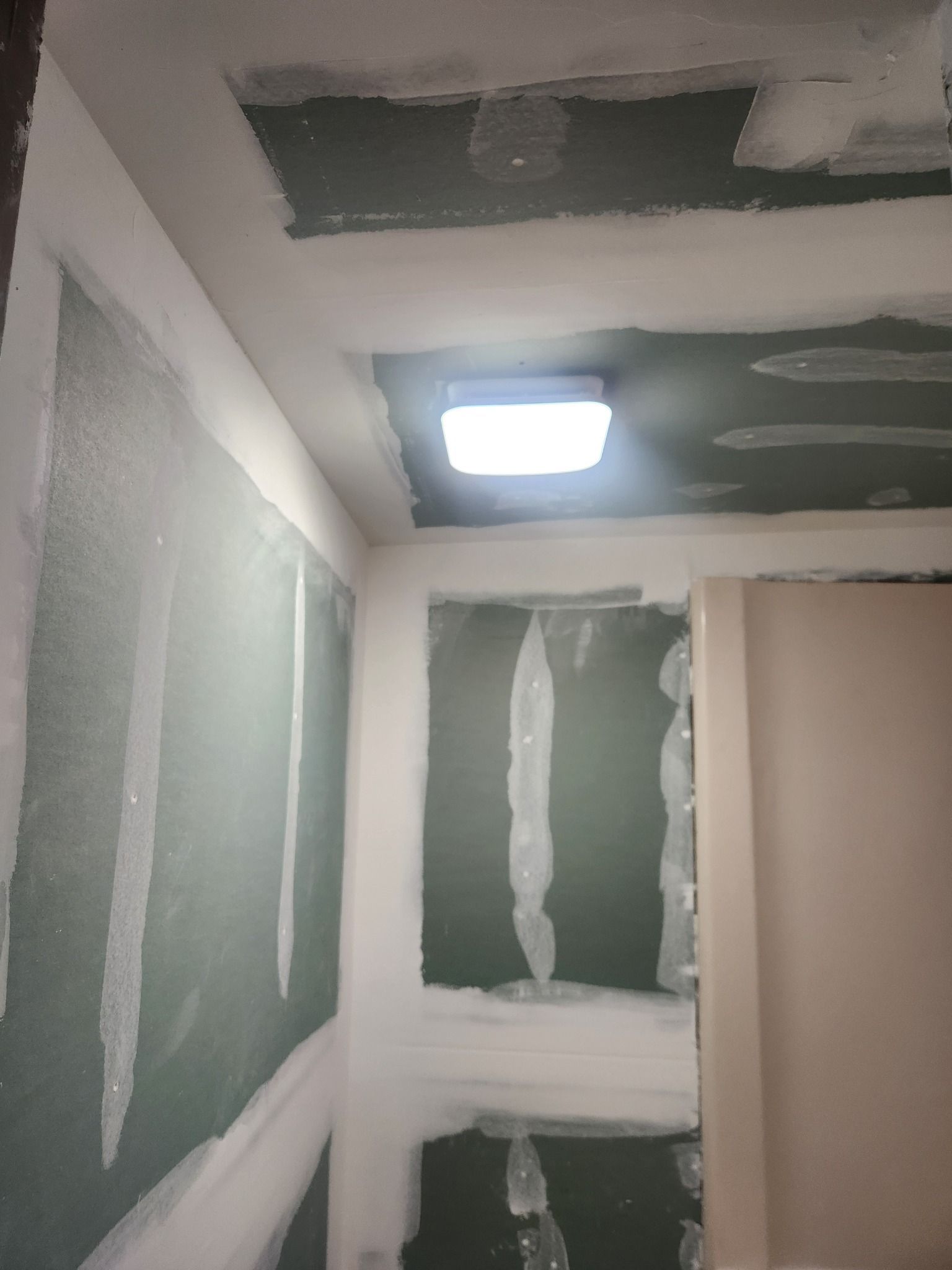 Interior room with unfinished drywall and a lit ceiling light.