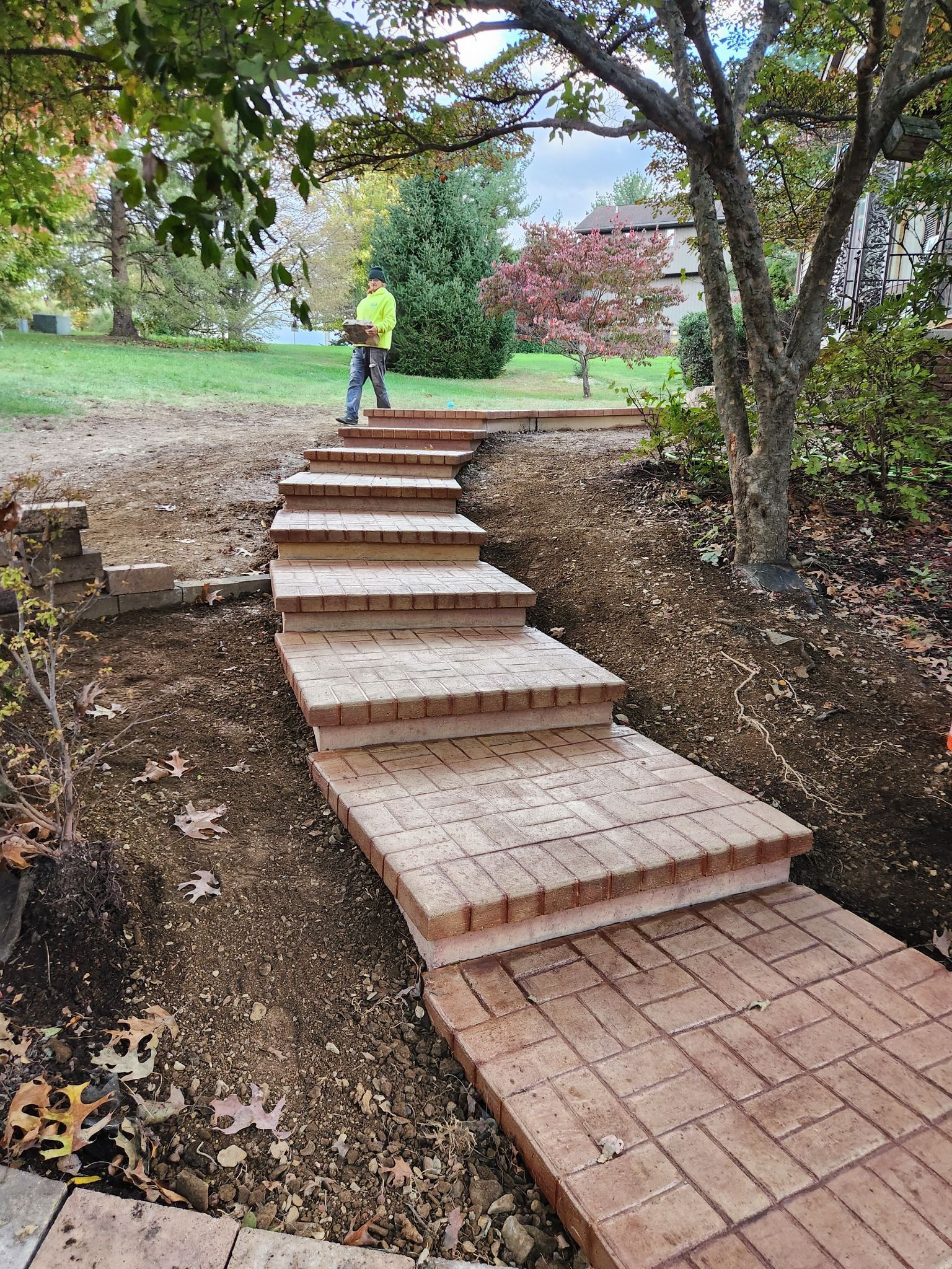 Brick steps and walkway leading uphill; person in yellow shirt ascends, surrounded by landscaping.