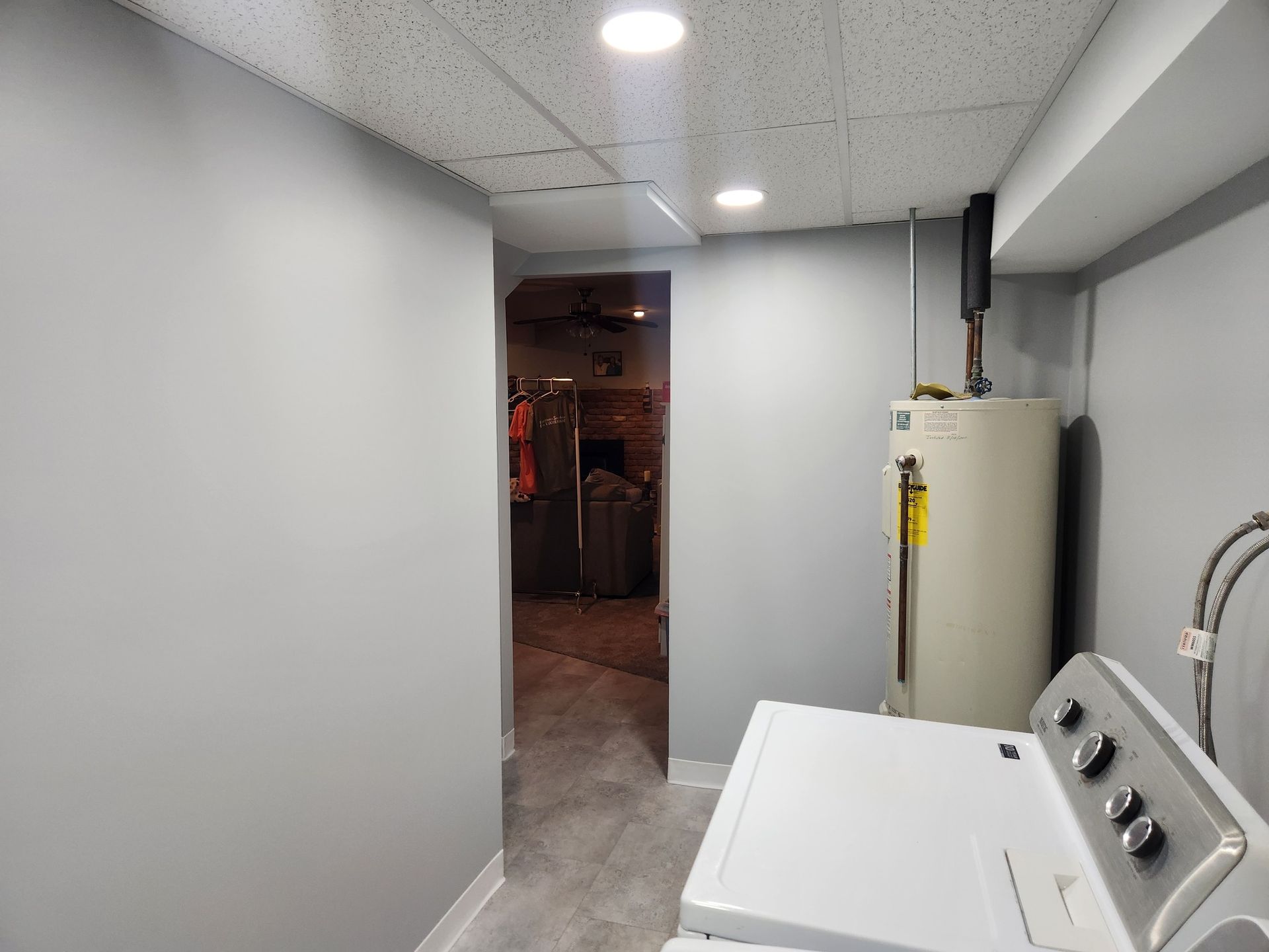 Laundry room with a washing machine, water heater, and hallway with gray walls.