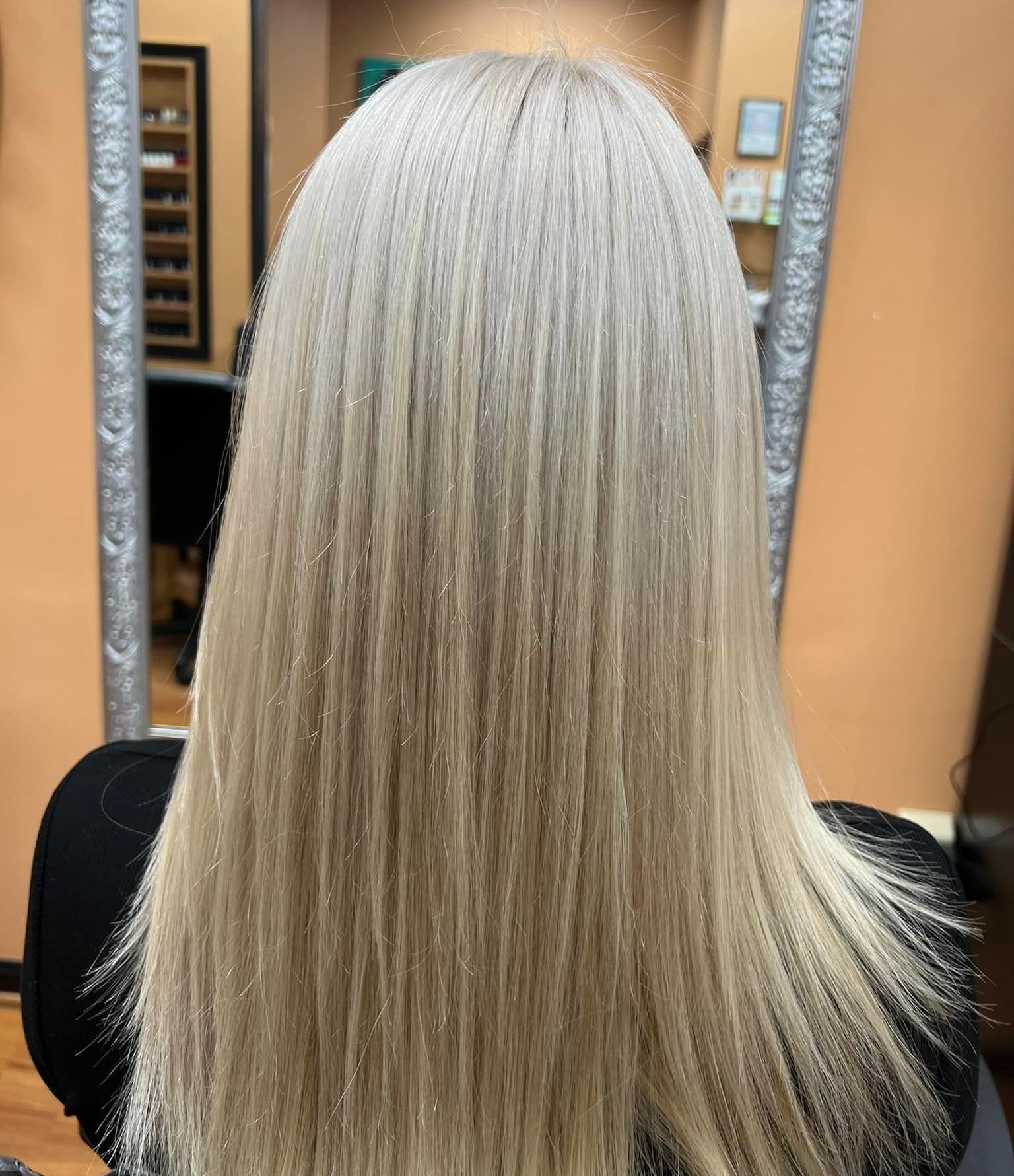 A woman with long blonde hair is sitting in front of a mirror.