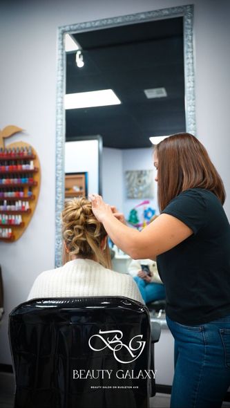 A woman is getting her hair done by a hairdresser in a salon.