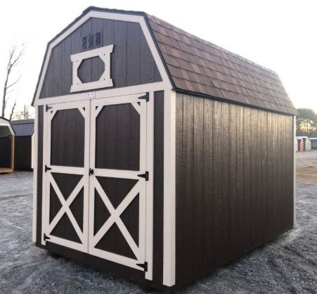 A brown and cream barn-style shed with a shingled roof and double doors.