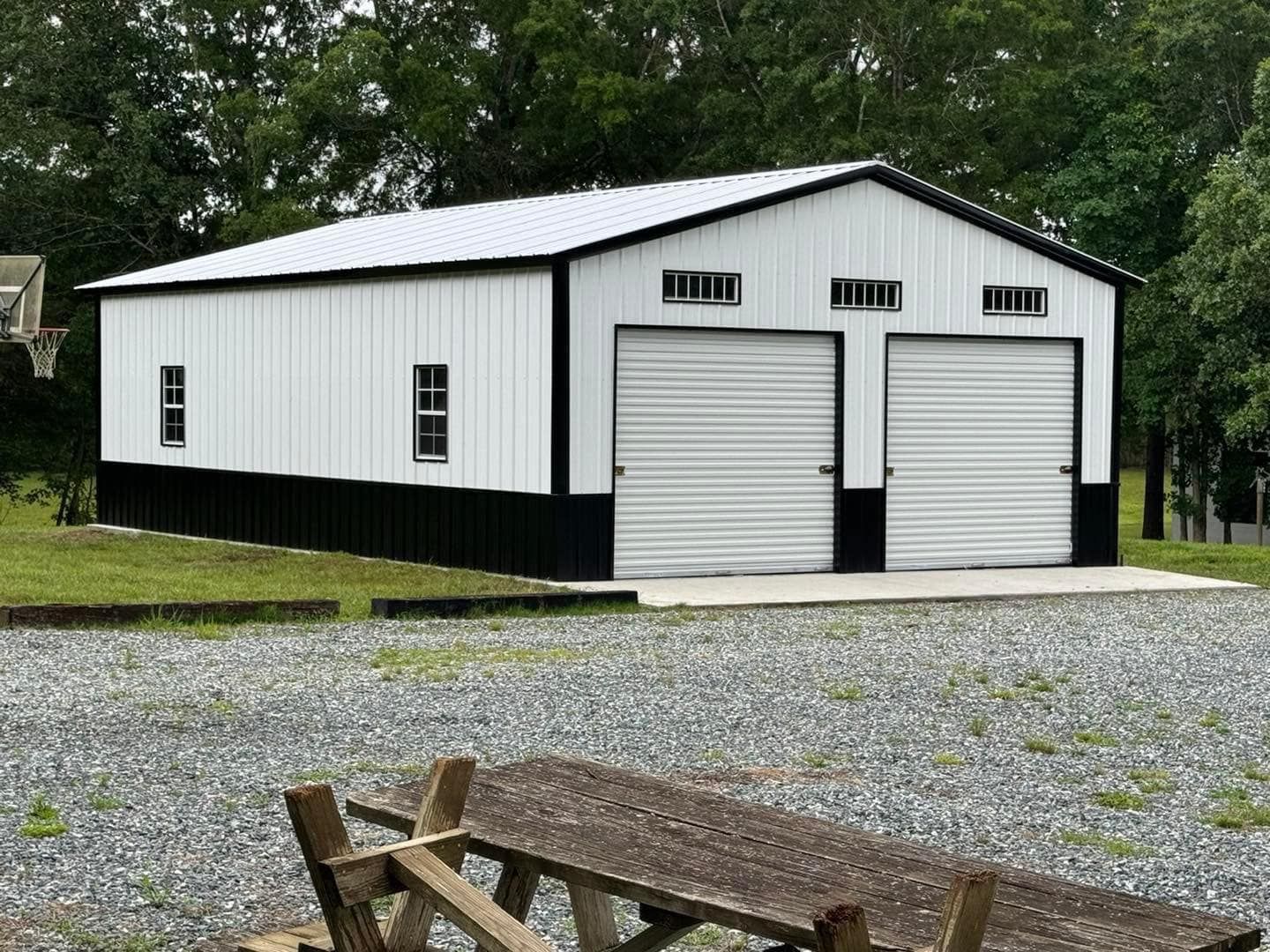 A two-car metal garage with a white and black exterior, two garage doors, and a small window.