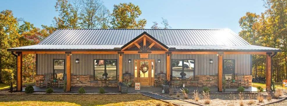 A single-story building with a metal roof, wooden supports, and stone accents.