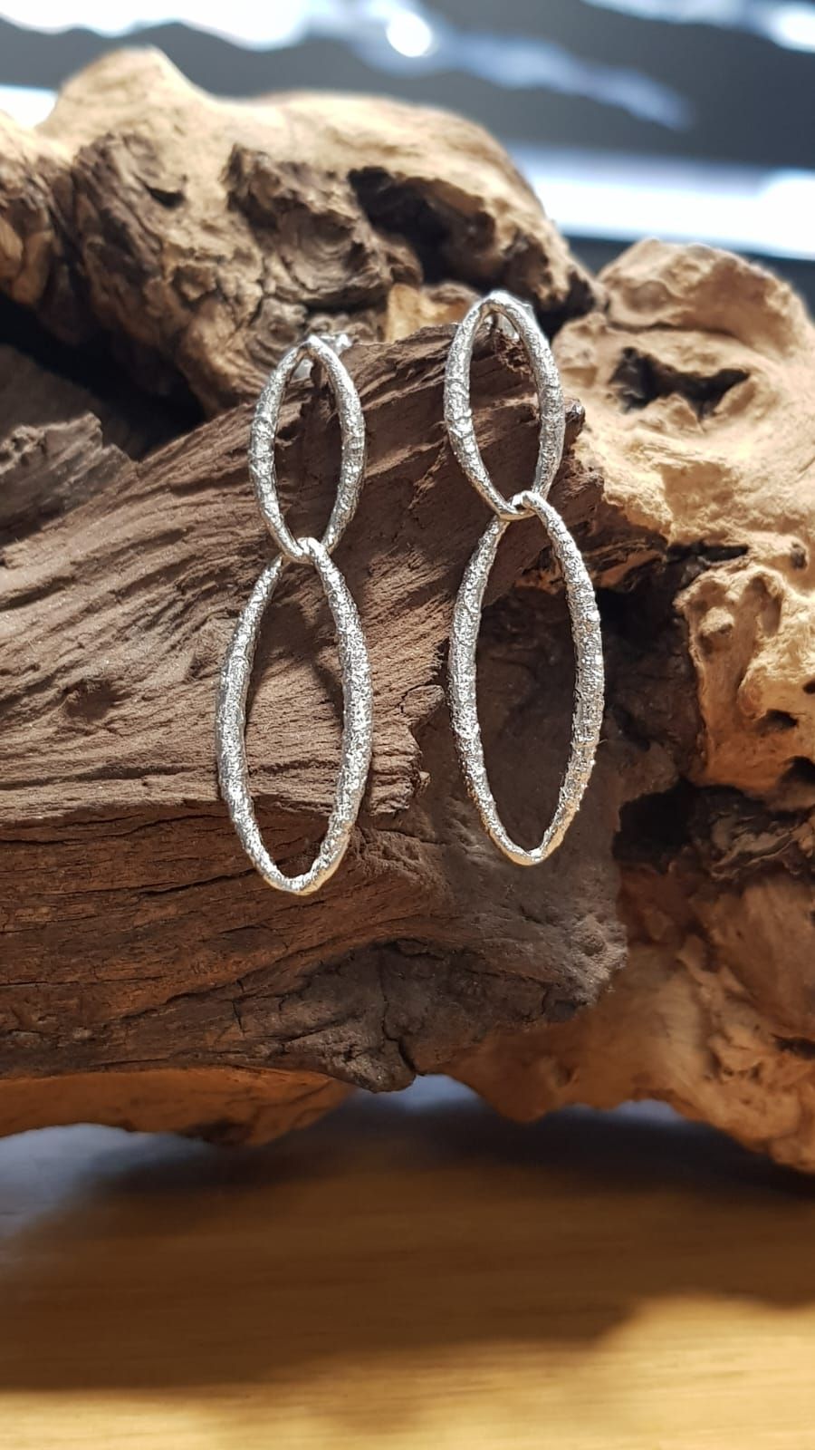 Collana in argento con pendente di perla su fondo in legno.