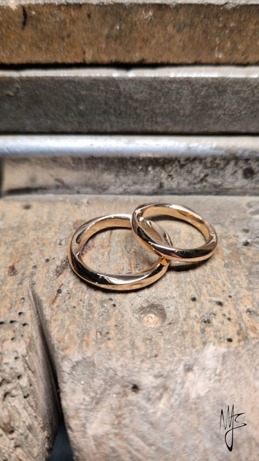 Due fedi nuziali in oro su una superficie di pietra testurizzata.
