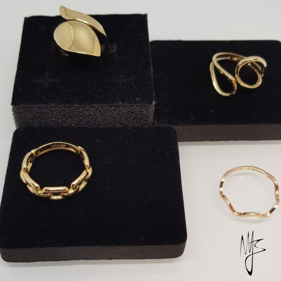 Quattro anelli d'oro esposti su cuscinetti di velluto nero.