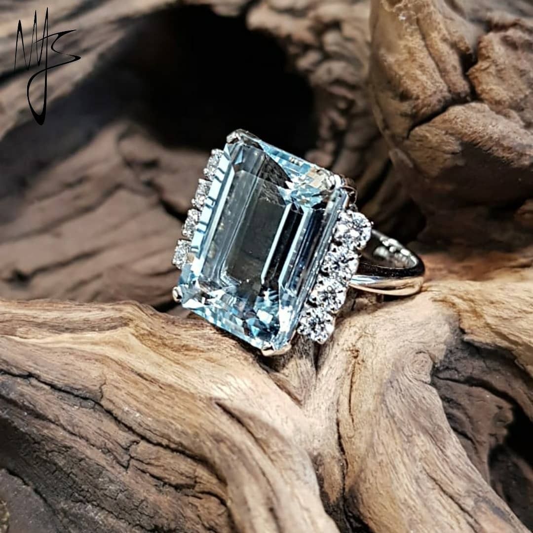 Anello con acquamarina e diamanti su legno galleggiante.