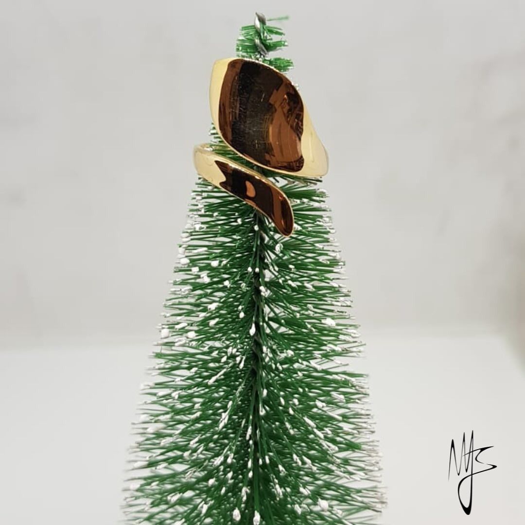 Anello in oro con intarsio marrone su un piccolo albero di Natale verde floccato.