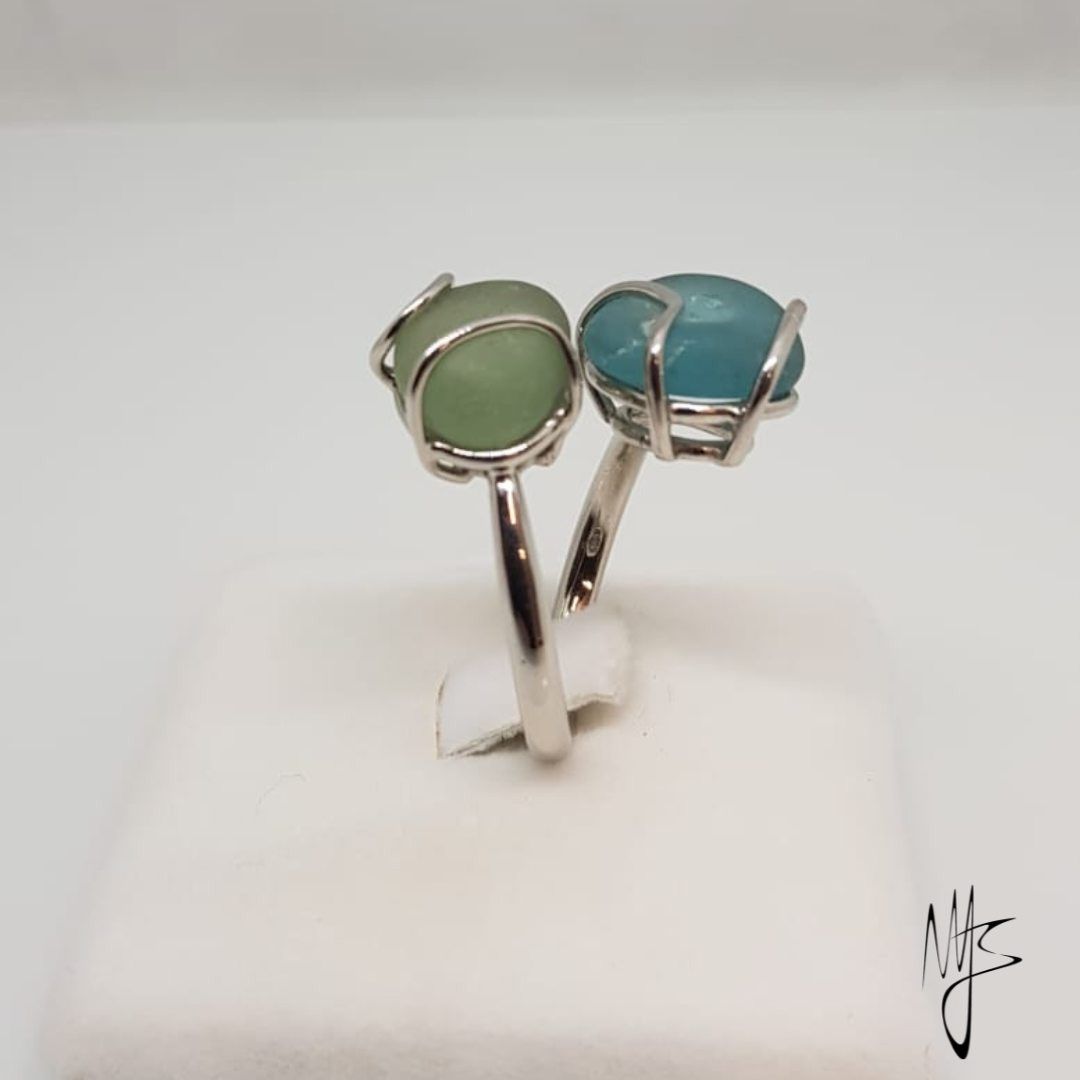 Anello in argento con due gemme, una verde chiaro e una blu, incastonate una accanto all'altra.