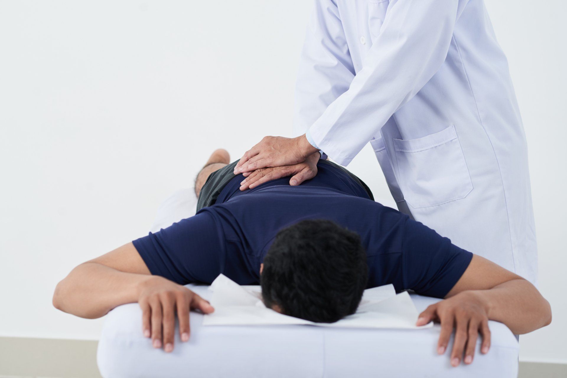 A man is laying on a bed getting a massage from a doctor.