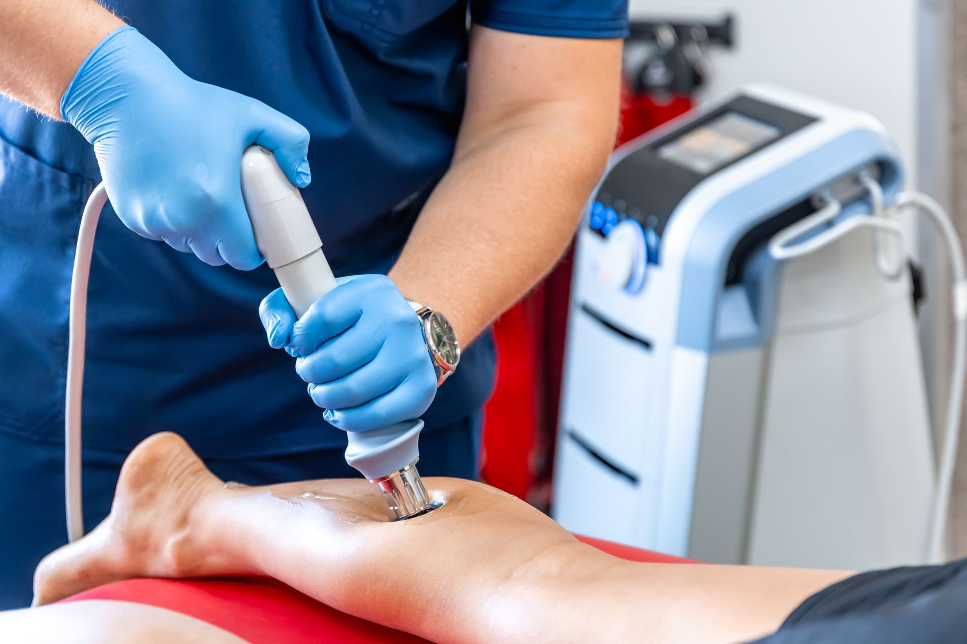 A doctor is using a machine on a patient 's leg.