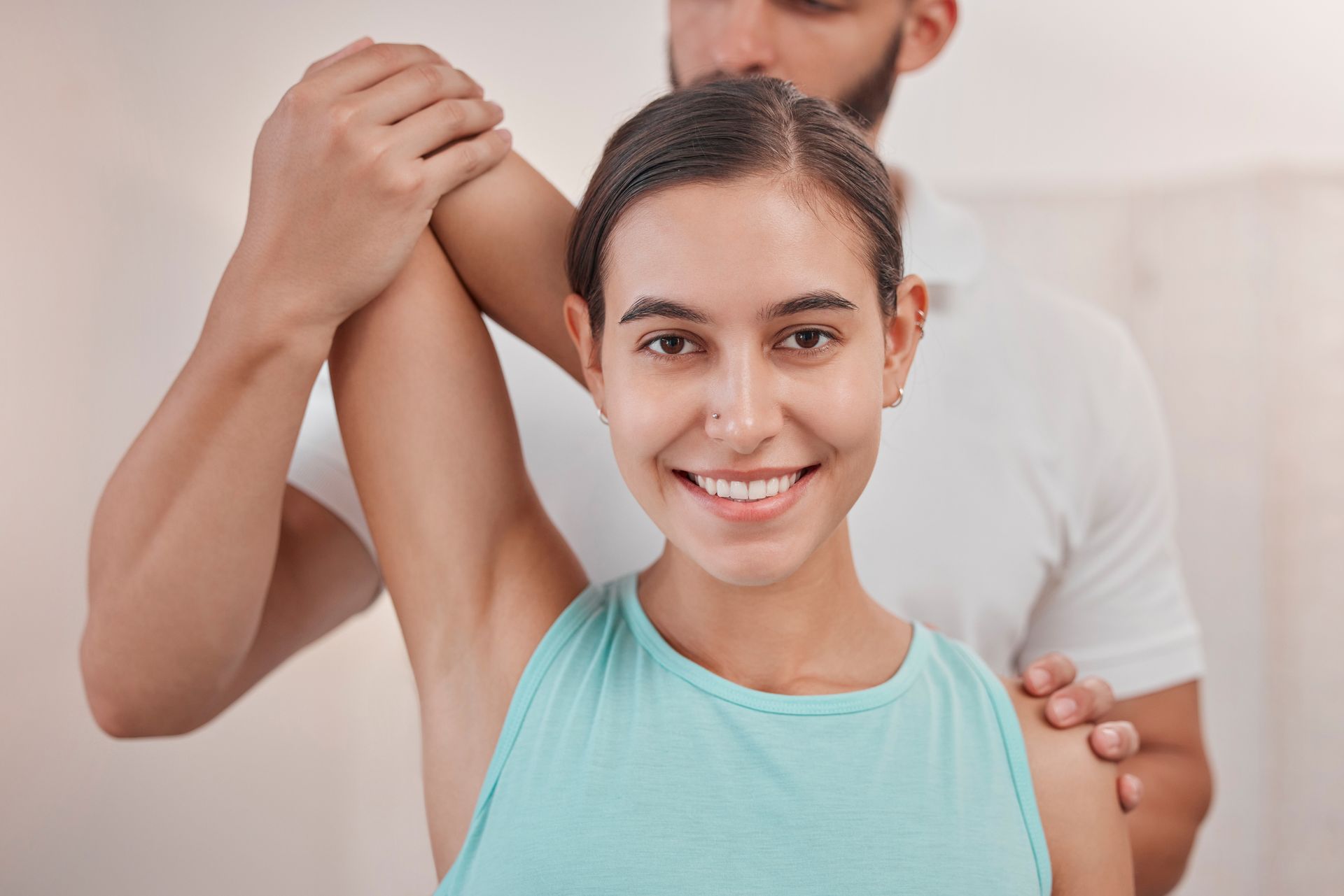 A man is stretching a woman 's arm while she smiles.