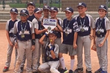 Baseball glove with ball on green grass, with blurred baseballs in the background.