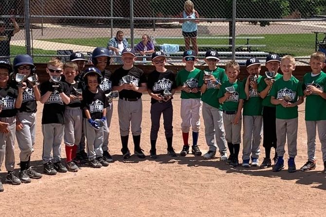 Baseball player sliding into home plate, catcher in front. Blue and gold uniforms, action shot.