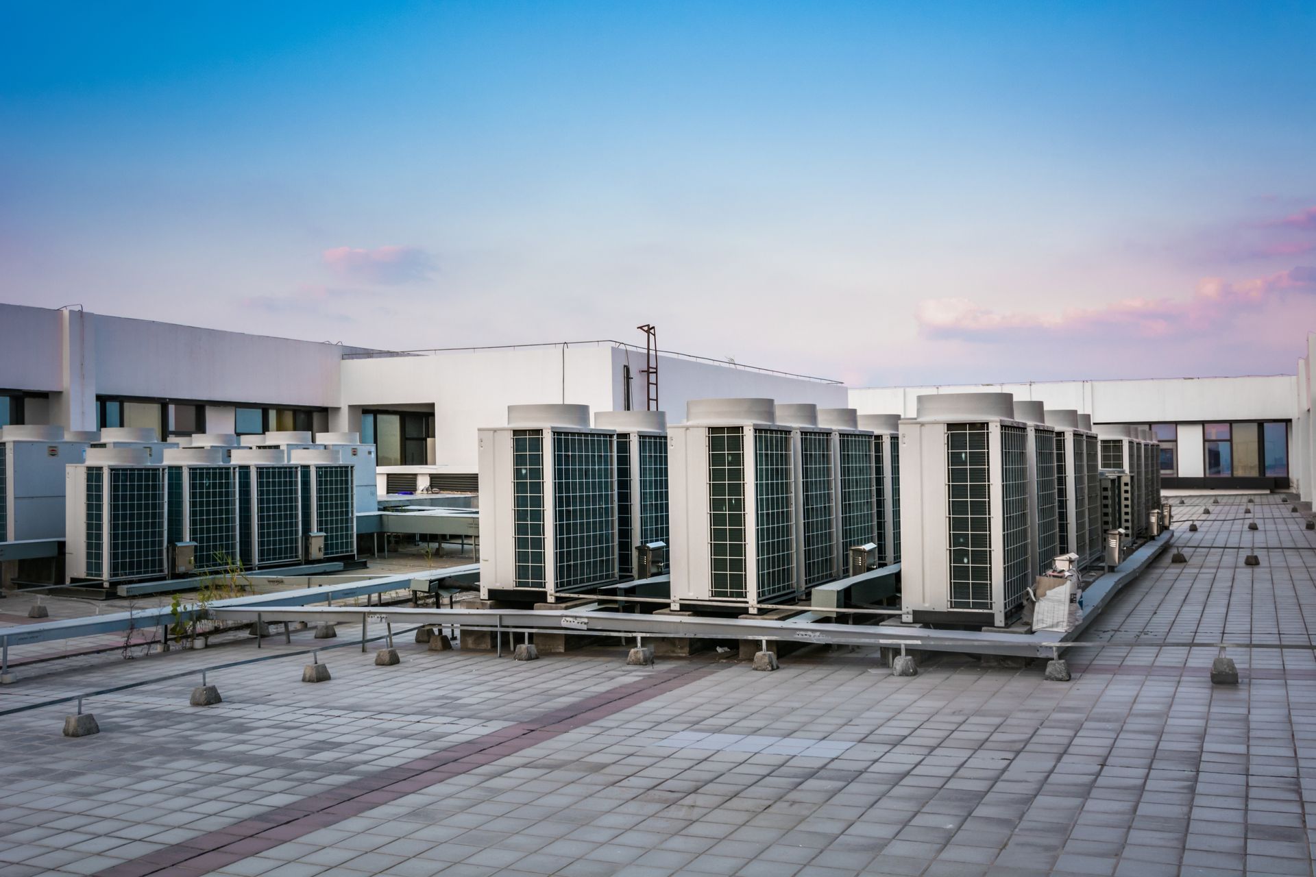 HVAC units on a flat rooftop against a blue and pink sky.