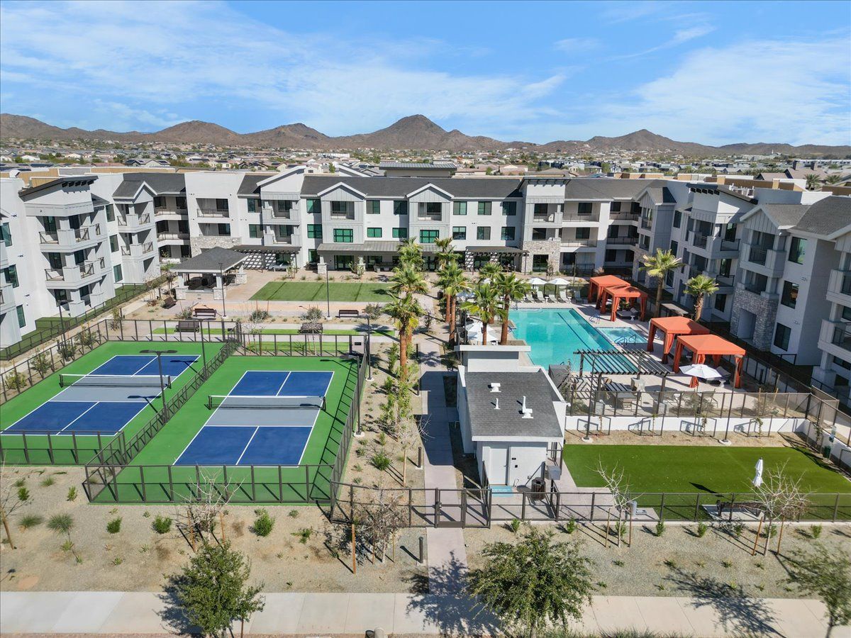 An aerial view of a large apartment complex with tennis courts and a pool.