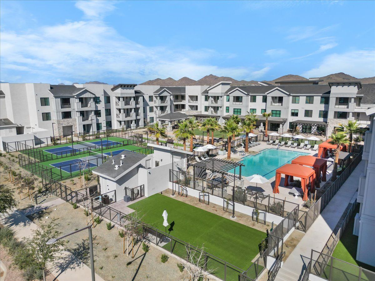 An aerial view of a large apartment complex with a swimming pool and tennis courts.