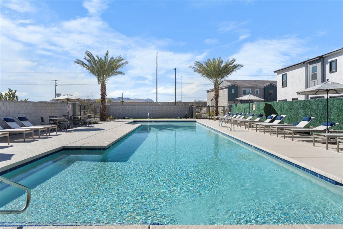 A large swimming pool surrounded by lounge chairs and palm trees.