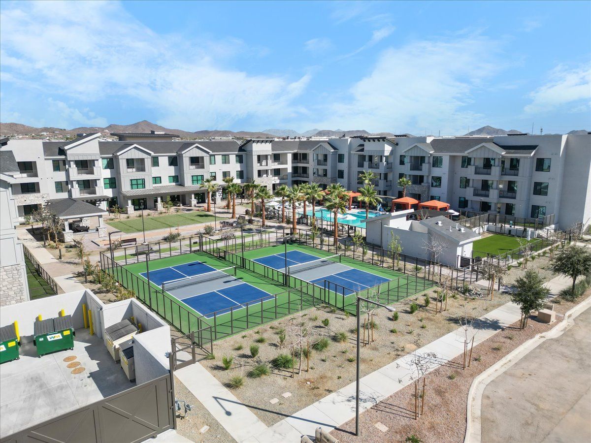 An aerial view of a large apartment complex with tennis courts and a pool.