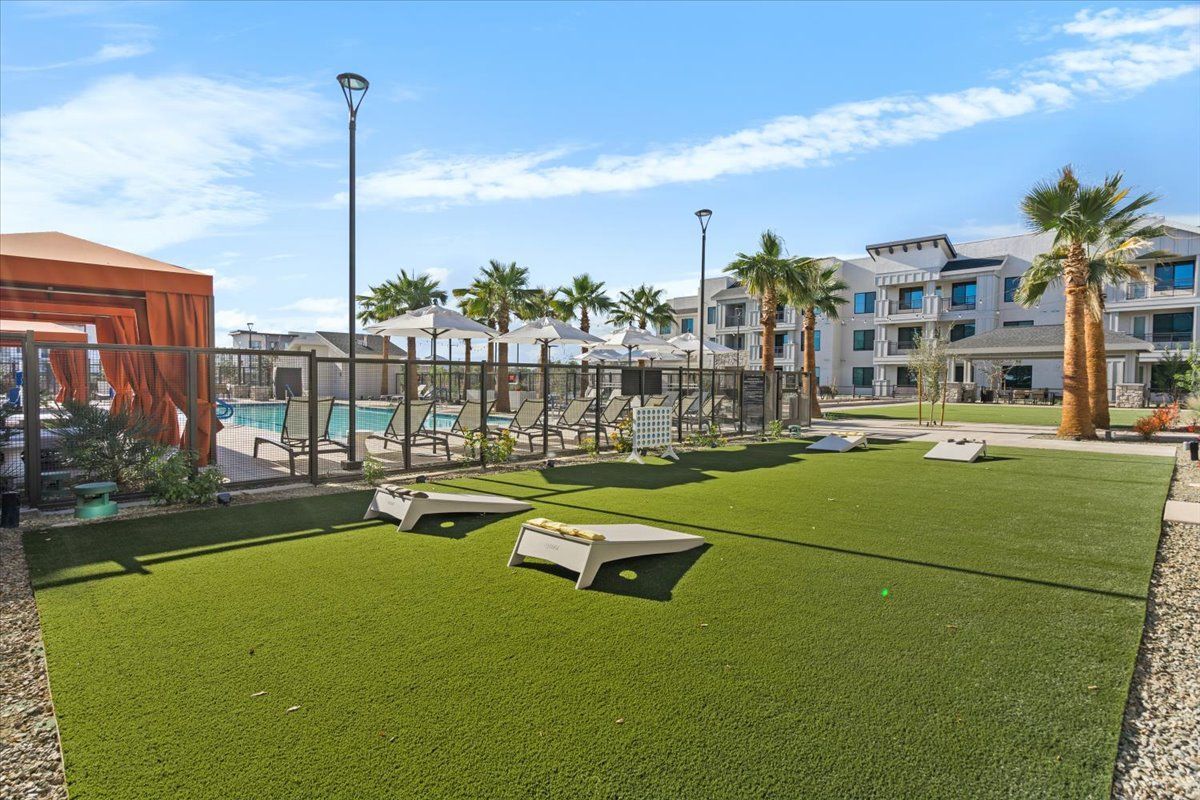 A large grassy area with a fence and a pool in the background.