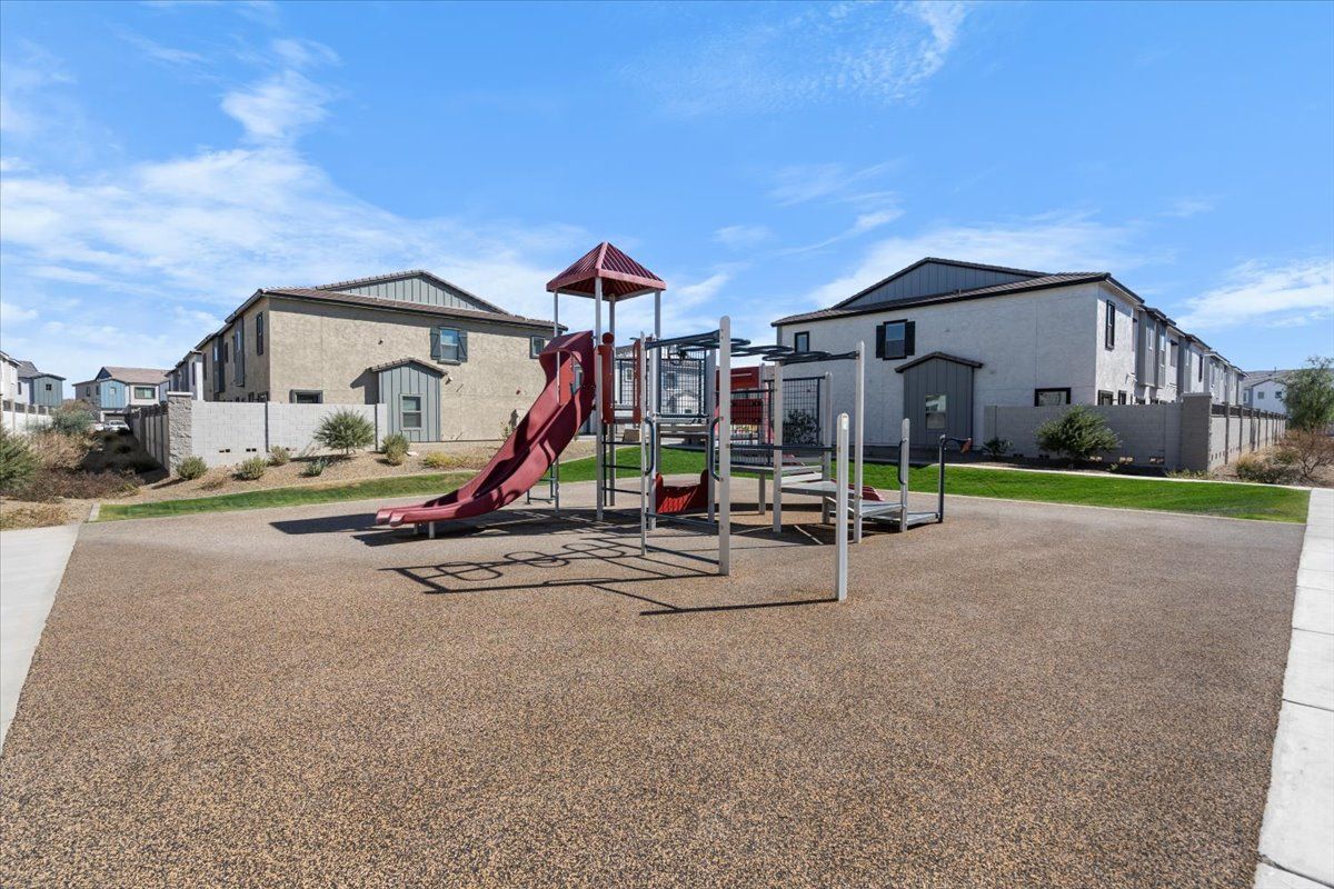 A playground with a slide and swings in front of a house.