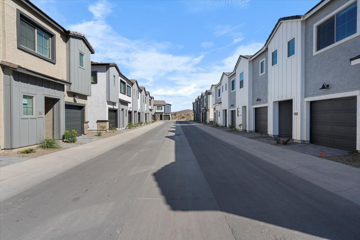 A row of houses with garages on the side of a street.