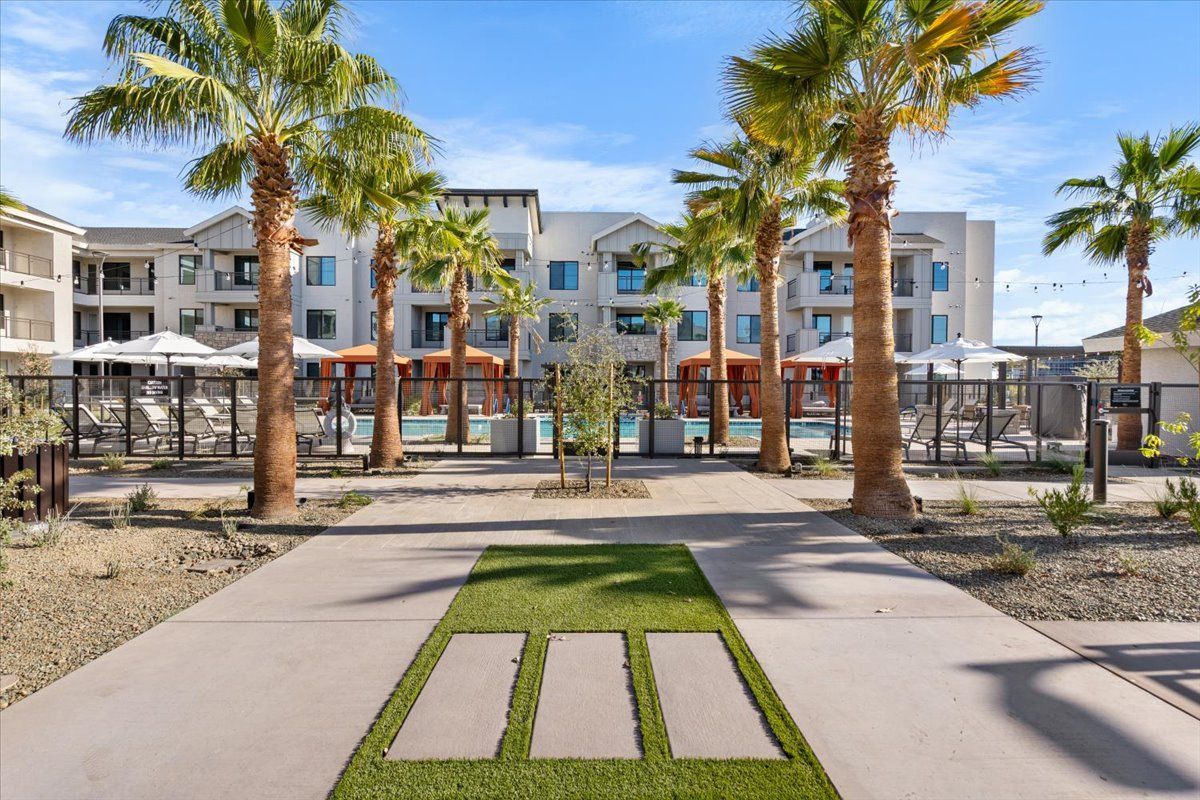 A building with a pool and palm trees in front of it.