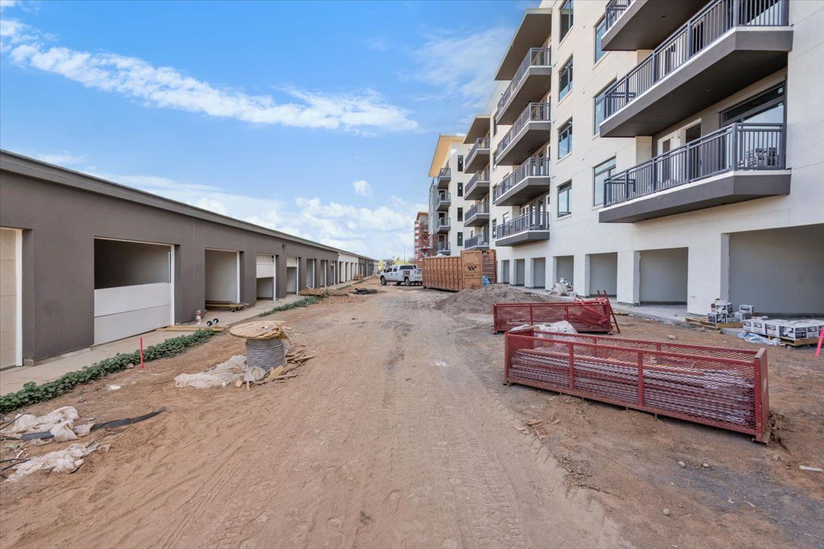 A building under construction with a dirt road in front of it.