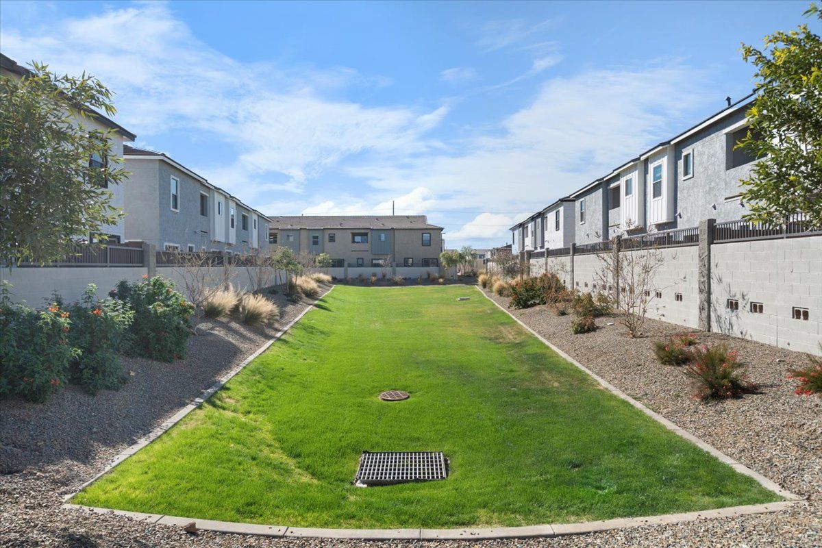 A large lawn with a drain in the middle of it in front of a row of houses.