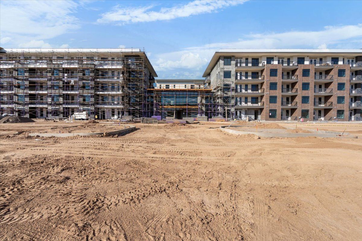 A large building under construction with a lot of dirt in front of it.