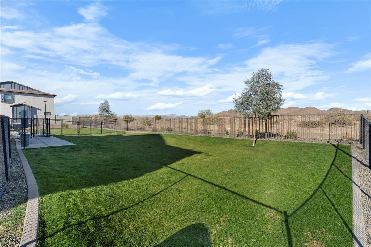 A large lawn with a fence around it and a house in the background.