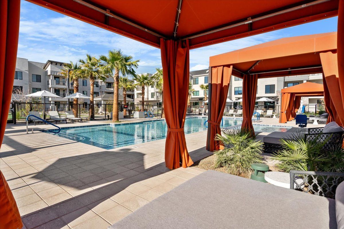 A swimming pool with a cabana in the foreground and a building in the background.