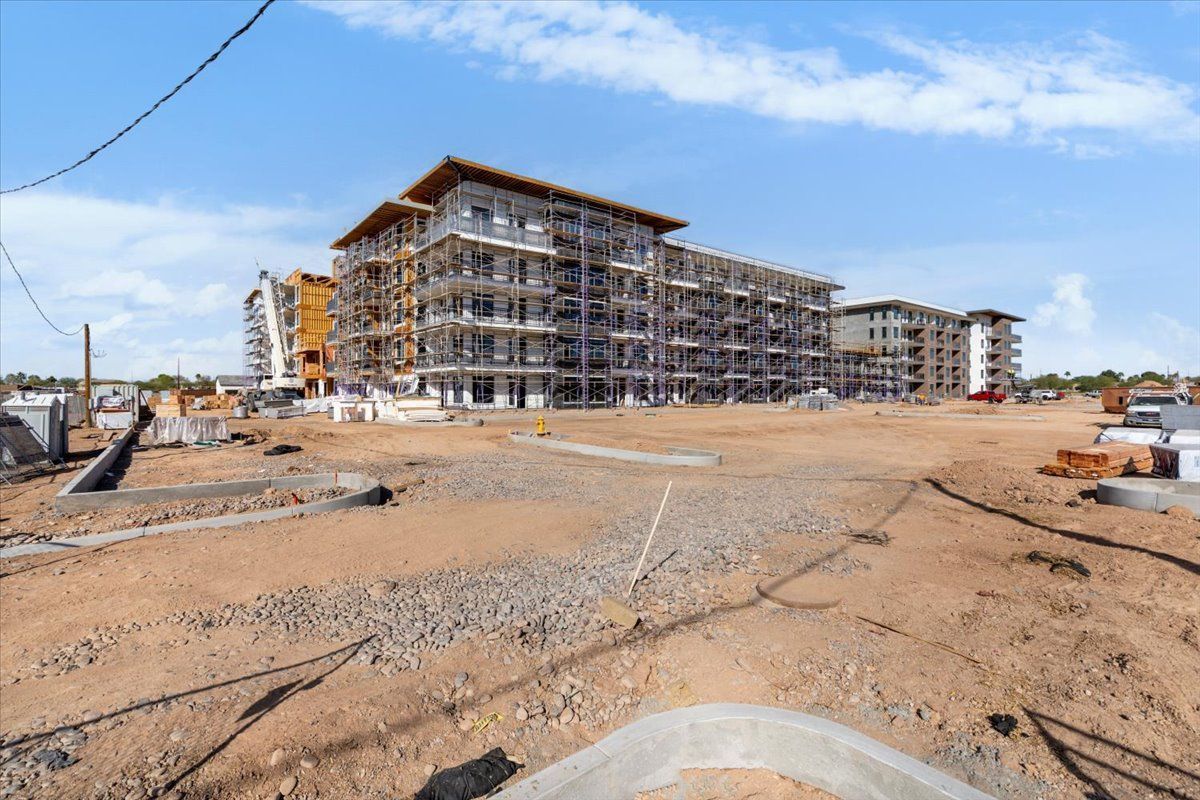 A large building is being built in the middle of a dirt field.