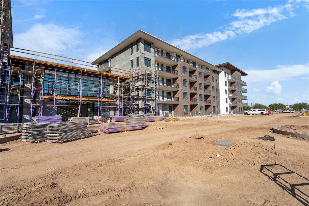 A large building is being built in the middle of a dirt field.