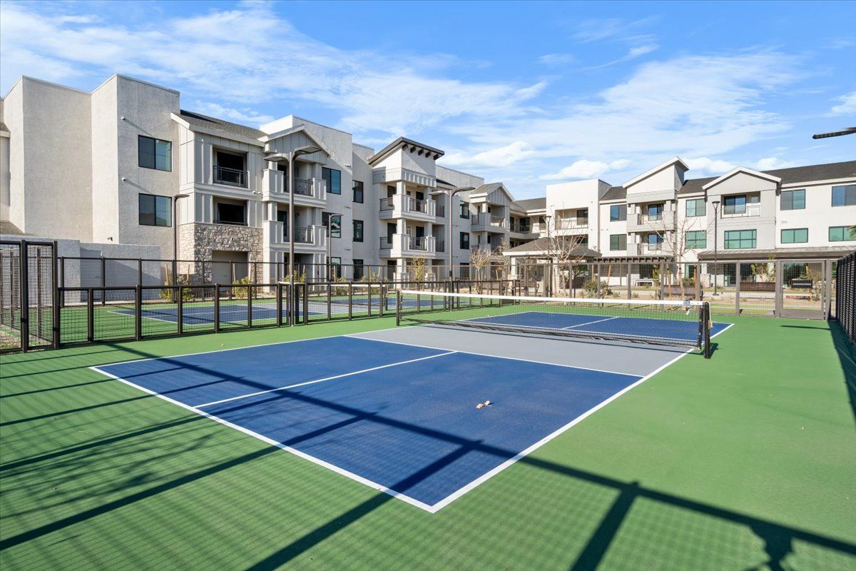 There is a tennis court in front of a building.