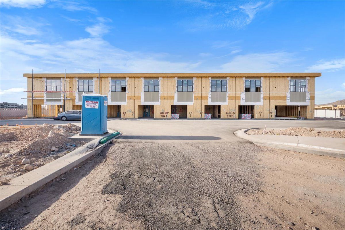 A building under construction with a blue portable toilet in front of it.