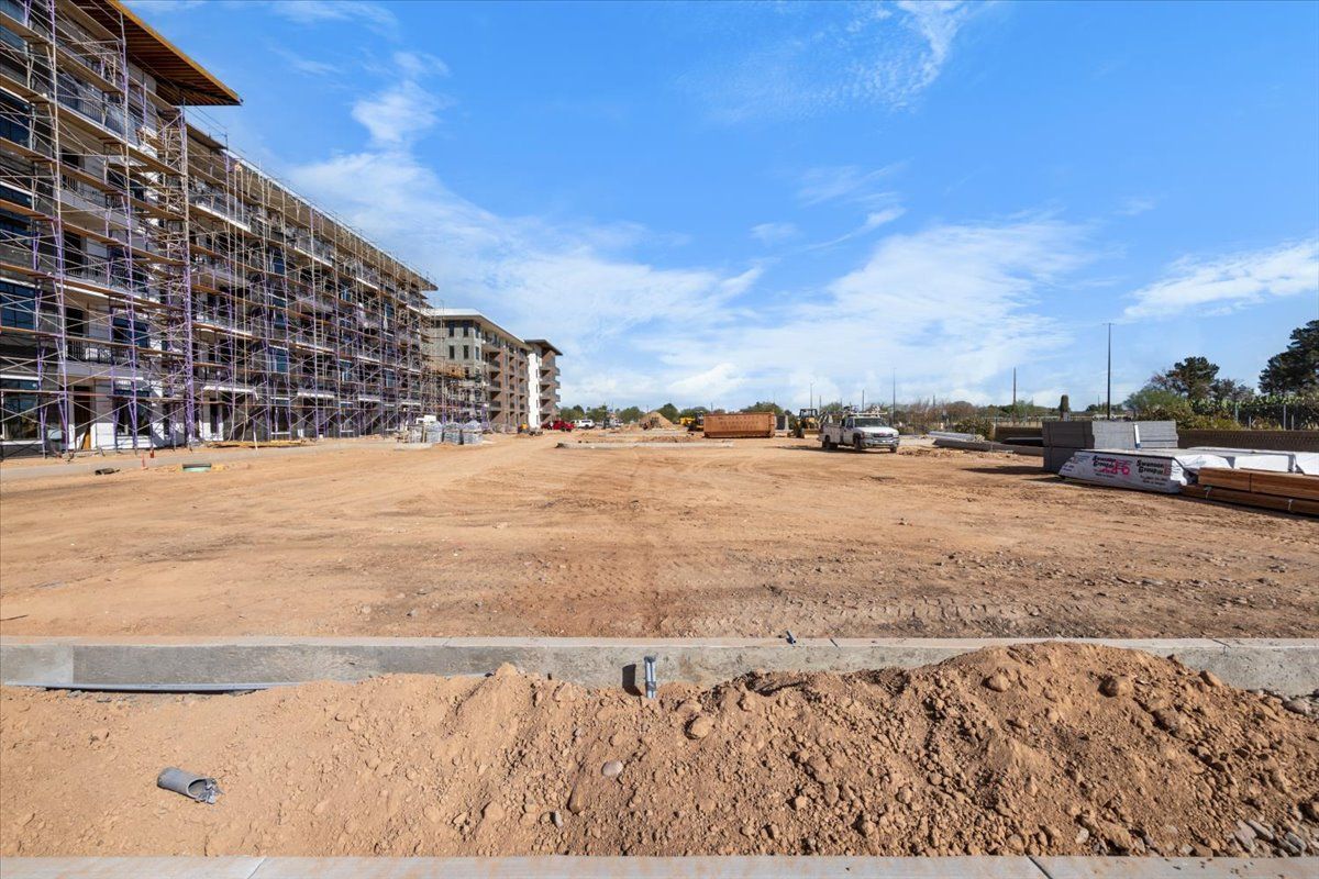 A large building under construction with a lot of dirt in front of it.