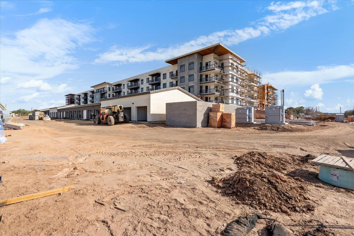 A large building is being built in the middle of a dirt field.