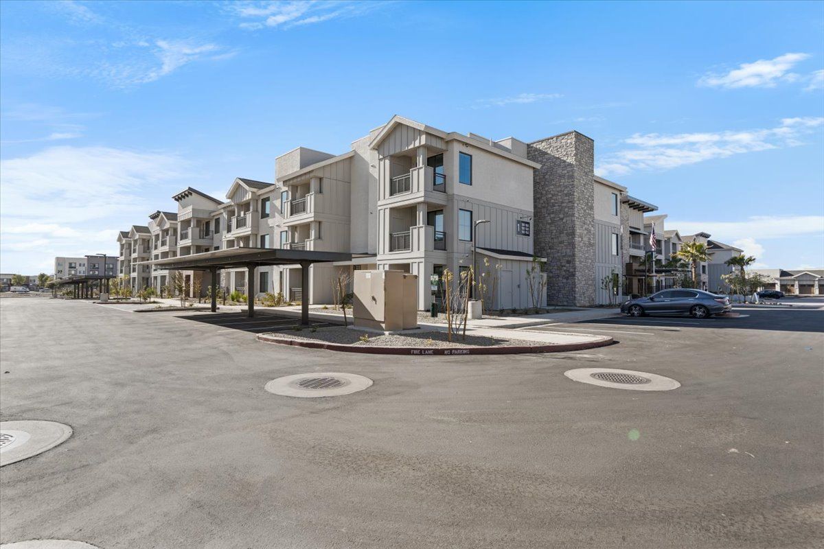 A large apartment building with a parking lot in front of it.