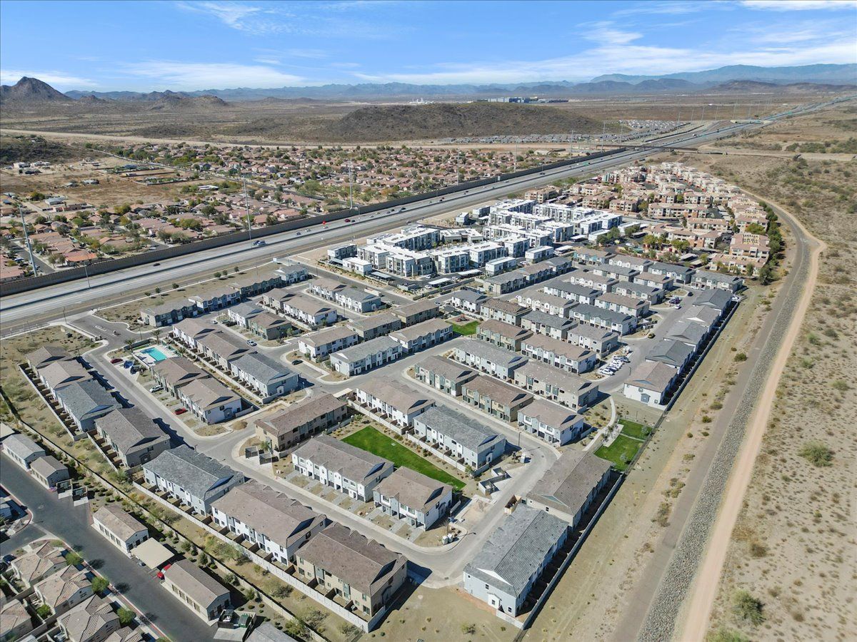 An aerial view of a residential area with a highway and mountains in the background.