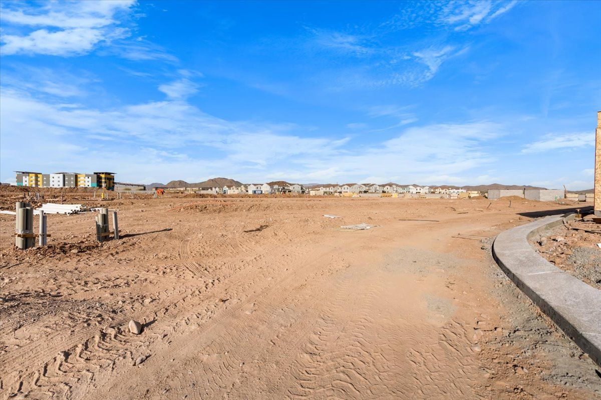 A dirt road leading to a construction site with a blue sky in the background.