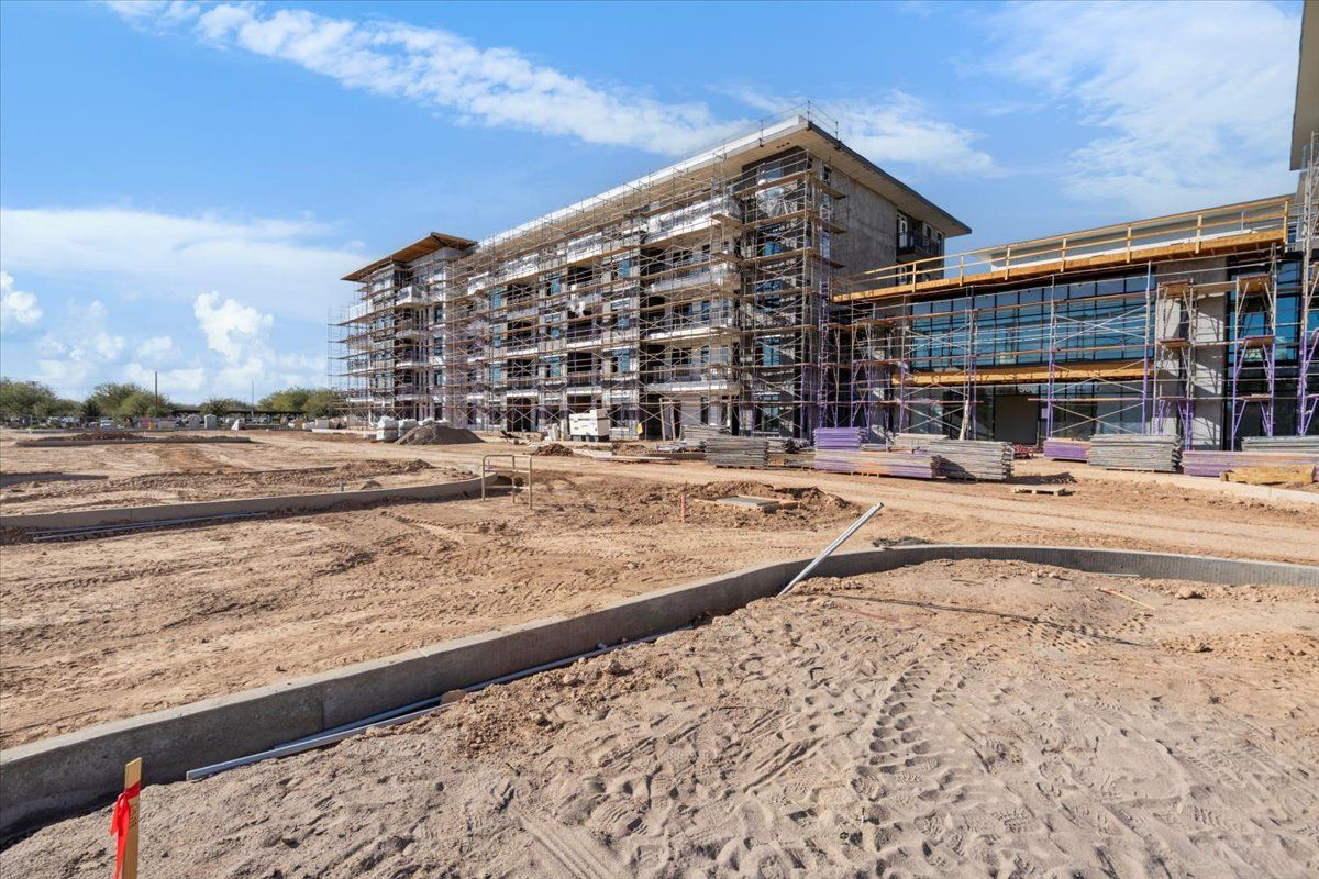 A large building is being built in the middle of a dirt field.