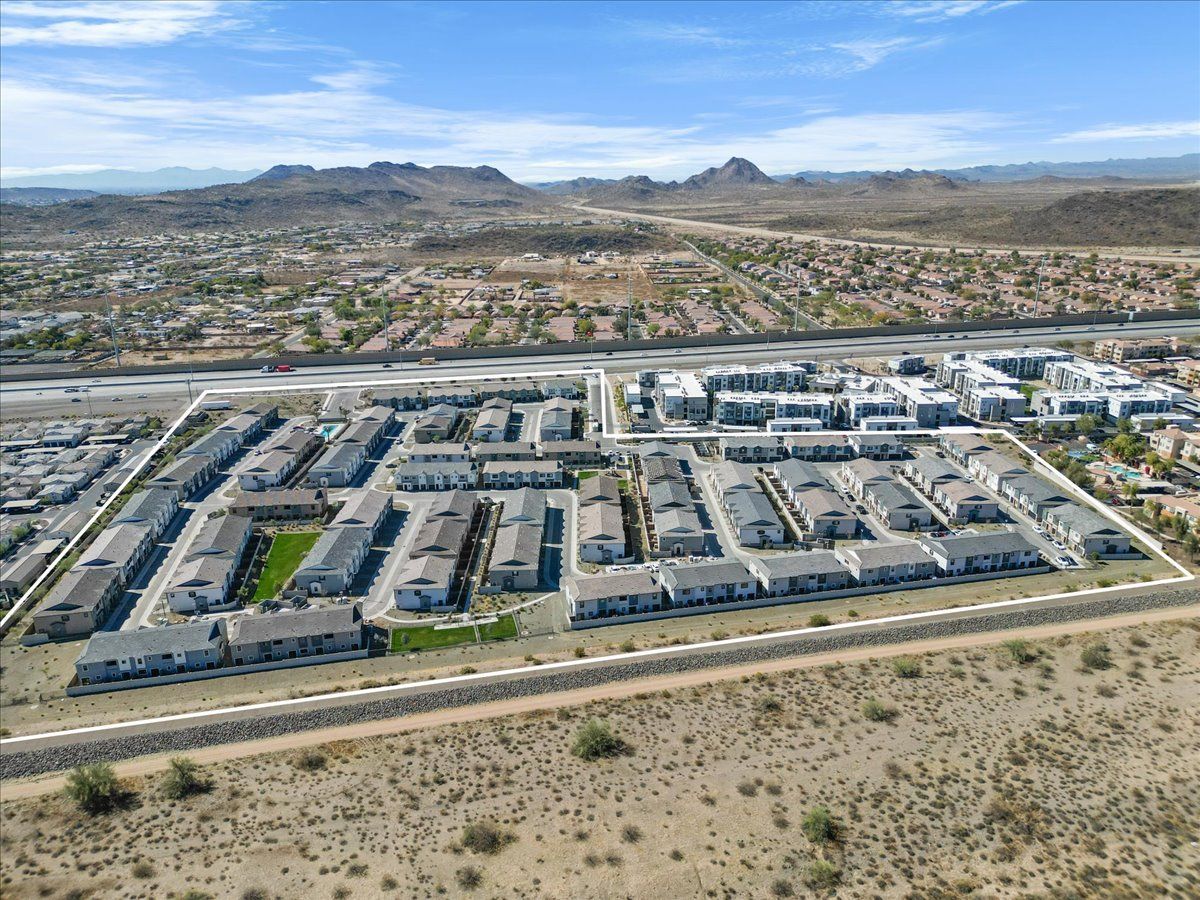 An aerial view of a residential area in the desert with mountains in the background.