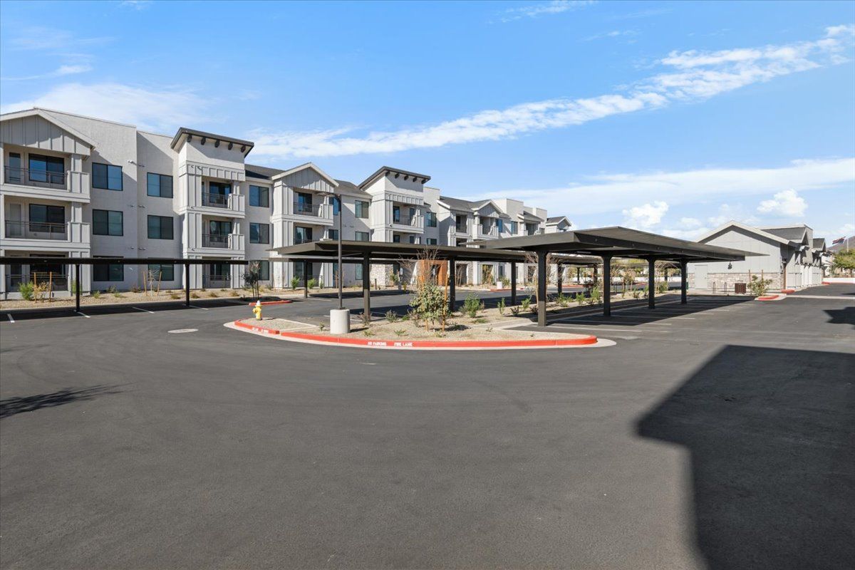 A large apartment building with a lot of parking spaces in front of it.