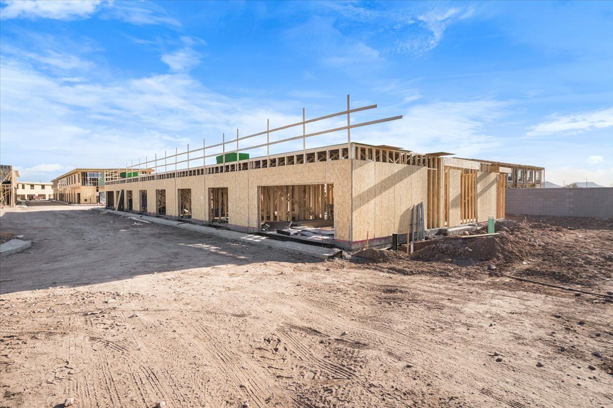 A large building is being built in the middle of a dirt field.
